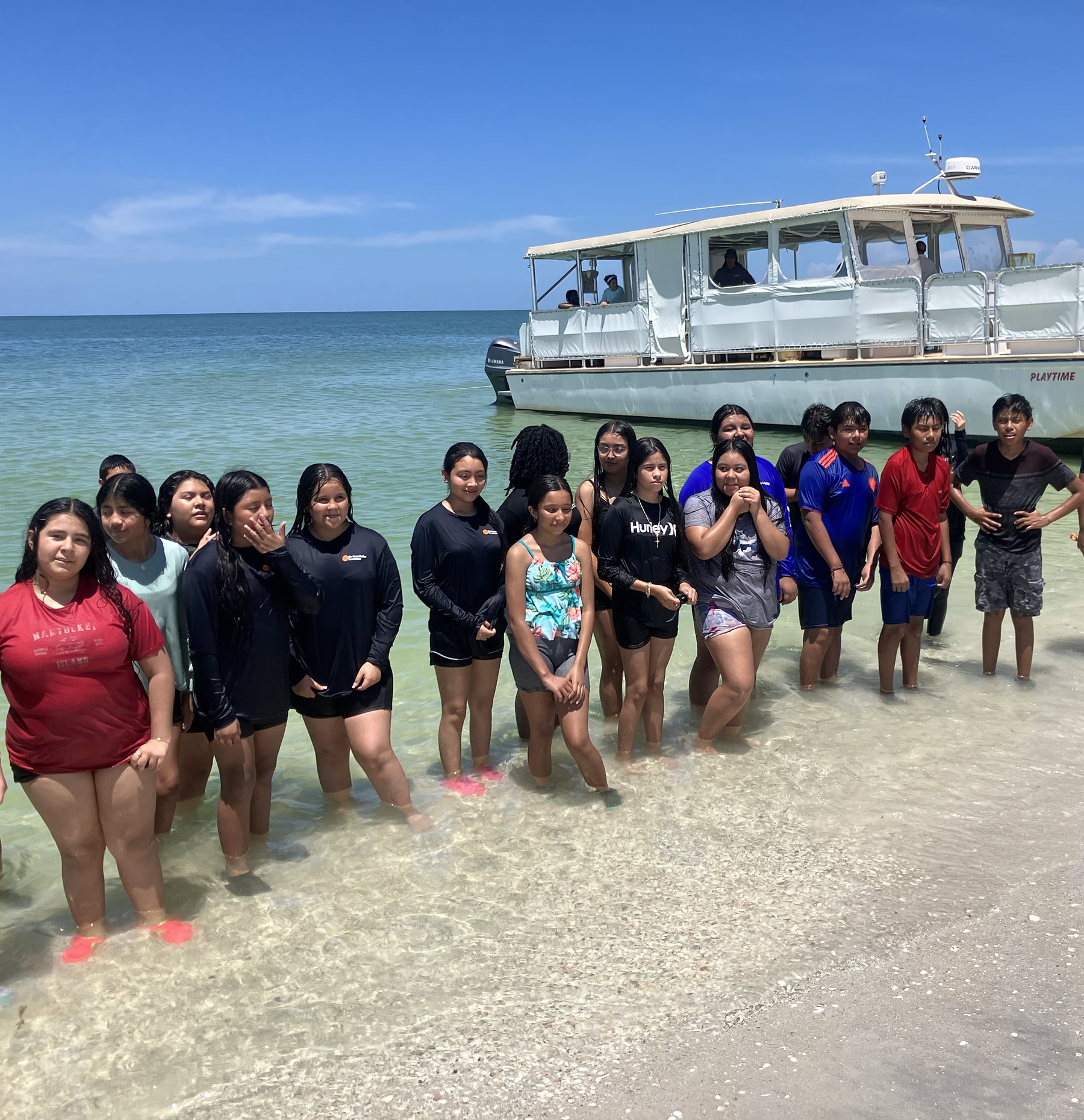 Kids standing on beach in front of boat during no child left on shore program
