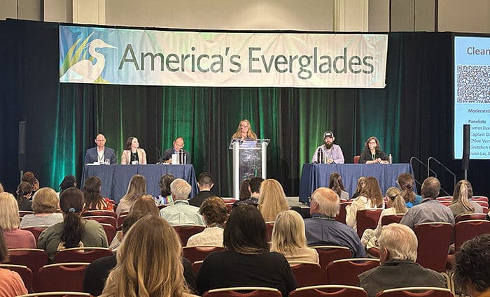 everglades conference 2024 image of panel speaking on stage with banner 'america's everglades' above them and crowd watching