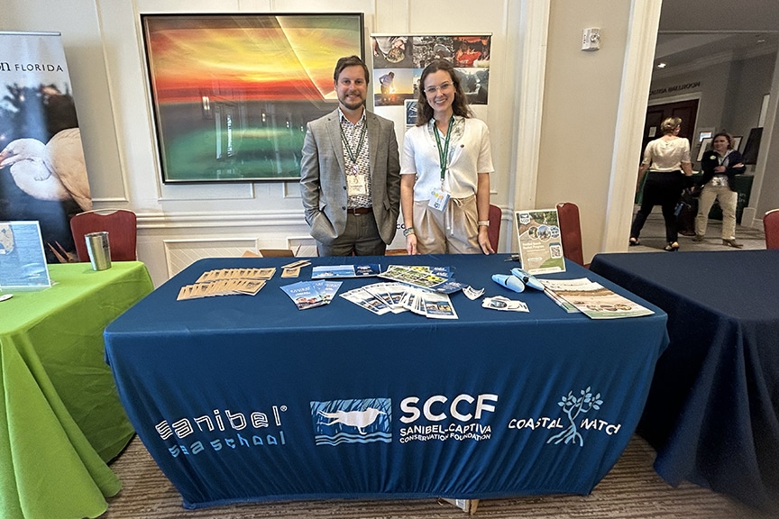everglades conference 2024, two staff stand at SCCF table indoors